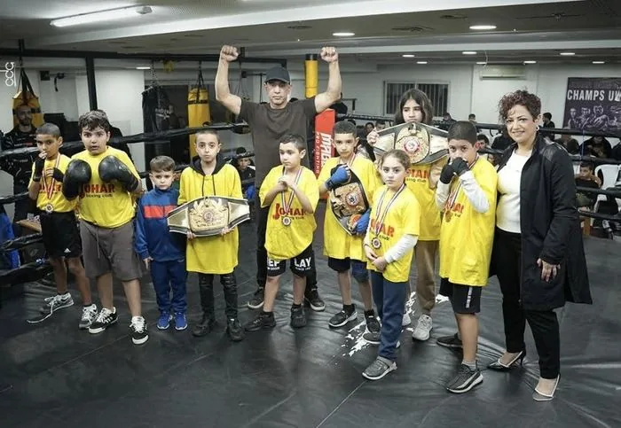 Young boxers holding Johar Lashin's championship belts